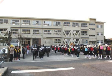 出迎えの皆と挨拶を交わしながら教室へ向かう児童(小学校正門) 出迎えの皆と挨拶を交わしながら教室へ向かう児童(小学校正門)