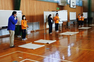 非常持出品・非常備蓄品リレーを説明する江口富中校長とチームHMBの中学生ボランティア 非常持出品・非常備蓄品リレーを説明する江口富中校長とチームHMBの中学生ボランティア